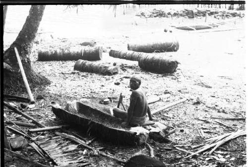 View of a man working on a dugout canoe