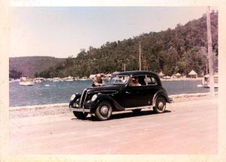 View of Oskar Speck standing with his BMW car at Killcare 