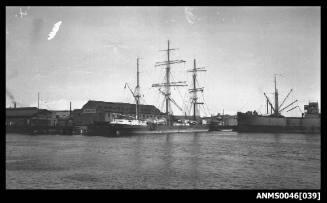 Masted barque alongside wharf with the bow section of SS EURELIA also visible