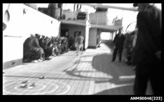 Group of people on boat deck watching a game of deck quoits