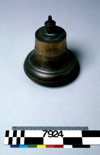 Brass bell with inscription reading CLAIRE CROUCH.