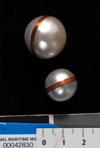 Two cultured spherical pearls with copper strips