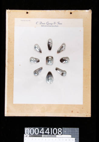 An album page with nine blister pearls attached with double-sided tape