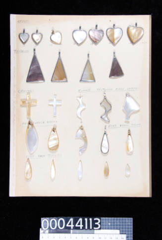 An album page with twenty- six pieces of trimmed and polished pearl shell, and pearl shell pendants, cut into various shapes, attached with double-sided tape