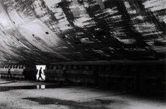 A dock worker crosses from one side of the ship to the other via a gap in the supporting blocks.