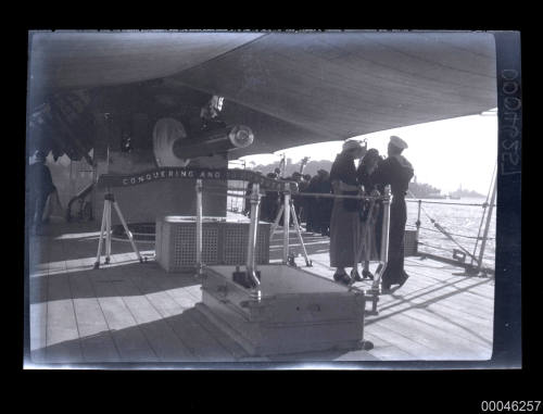 Visitors on board a naval ship with the motto 'Conquering and to Conquer'