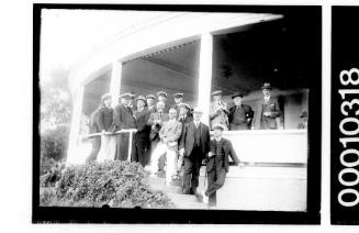 Men in yachting uniforms standing on the verandah of an unidentified yacht club, Probably RSYS.