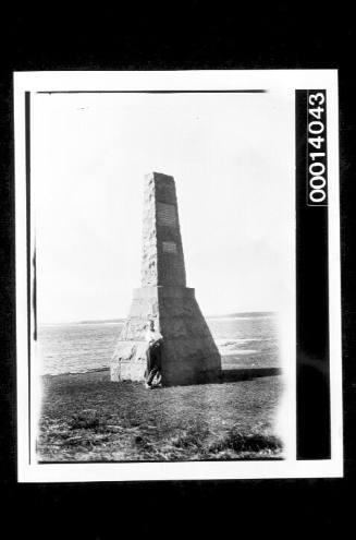 Man leaning on a seaside memorial