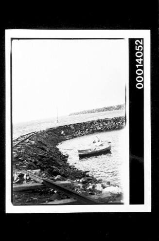Railway tracks along a curved breakwater, dinghy moored beside