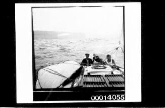 Crew at the stern of yacht UTIEKAH II, headlands in the distance
