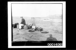 A man sitting on luggage on a wharf