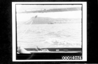 Small cargo ship at sea, headlands in the distance