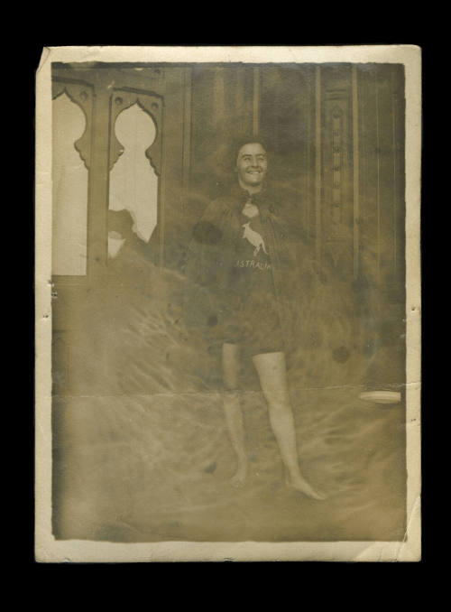 Black and white photograph of Beatrice Kerr, standing wearing a cape and swimsuit with a kangaroo and Australia written on it