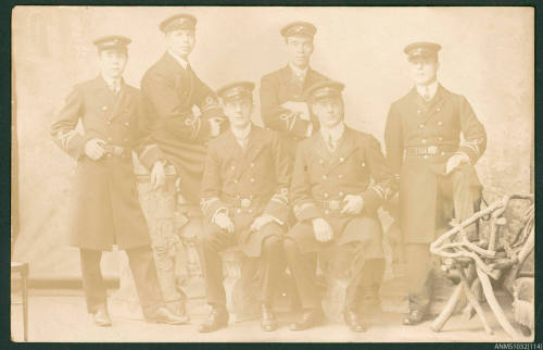 Postcard featuring a black and white photograph of six men in uniform