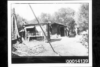 Three men beside a bush shack