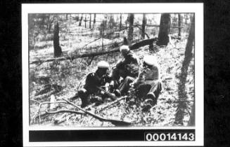 Men sitting in the bush with rifles