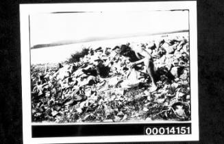 Washing clothes in a basin on a rocky shore