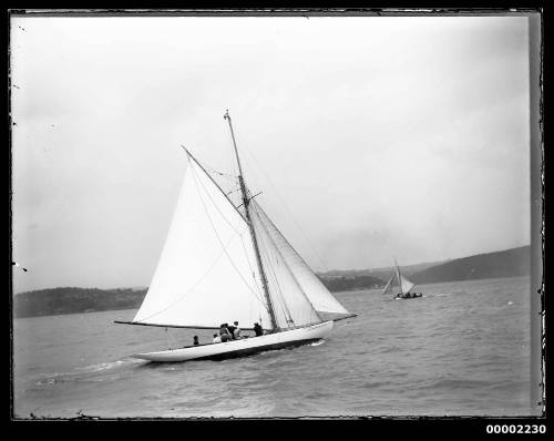 A starboard view of white-hulled gaff cutter under sail with the crew visiblie in the cockpit