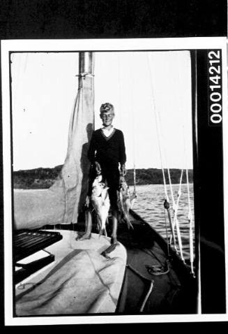 Boy on the deck of yacht UTIEKAH II holding his catch