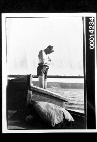 Man standing on the deck of a yacht beside a sail