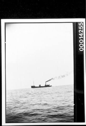 Small cargo ship at sea, smoke puffing from its funnel