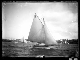 Yacht on Sydney Harbour, with 18-foot skiffs and a four-masted ship in the background