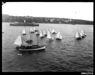 Racing skiffs pass a sailing boat on Sydney Harbour