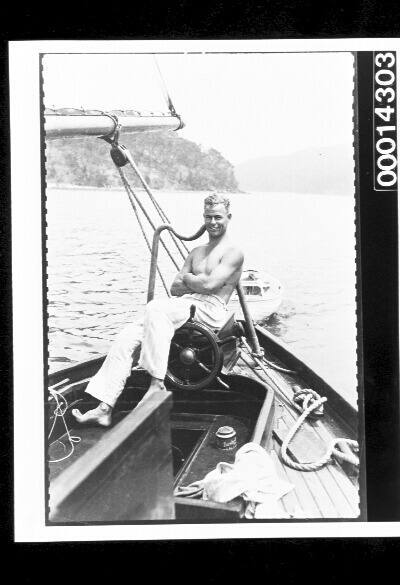 A young man relaxes at the wheel of a yacht