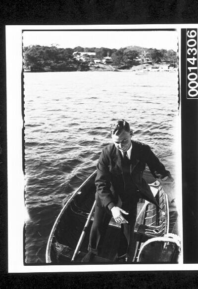 Young man dressed in a suit boarding a yacht from a dinghy