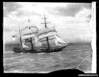 Three-masted barque underway with reduced sail