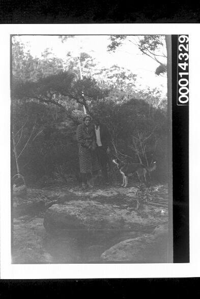 Young woman and man on a picnic with a dog in bushland