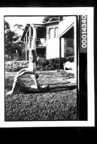 Two young boys in an acrobatic pose on grass