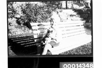 Young boy holding a cat on a garden seat