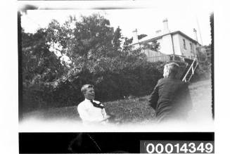 Two young men taking in a park, a house is in the distance