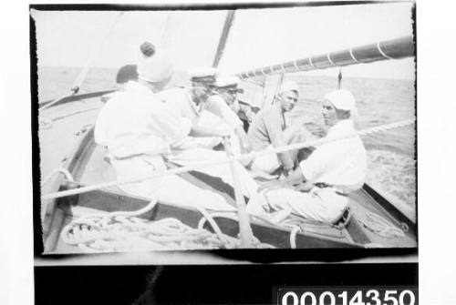 Men on the deck of a yacht under sail listing to starboard