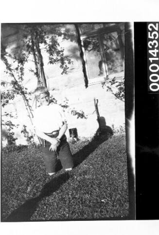 Young boy kneeling on grass outside a home