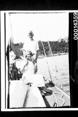 A young couple on the deck of a yacht just off shore