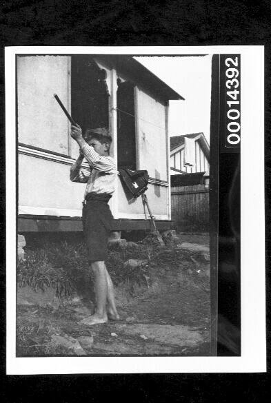 Boy with a rifle in a suburban backyard