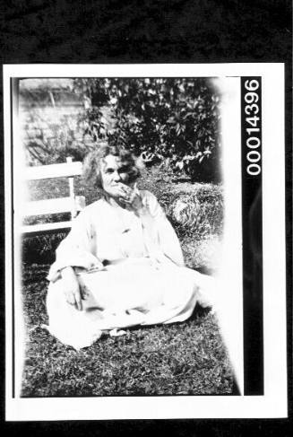 Woman sitting on grass smoking a cigarette