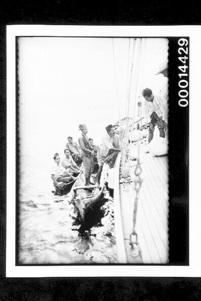 Men loading bags from canoes onto SIRIUS off Buton, Indonesia
