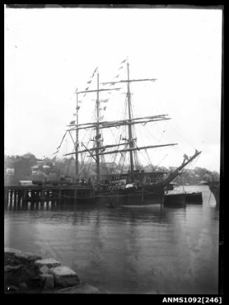 A three masted barque moored alongside wharf