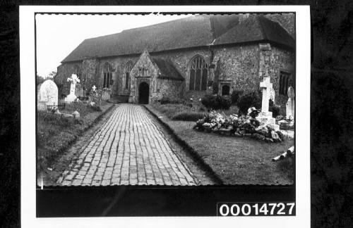 A paved path leading through a graveyard to a church door, England