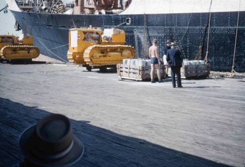 Slide depicting three men inspecting pallets at the dock