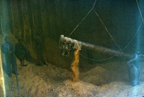 Slide depicting two men watching the loading of sand into the cargo area