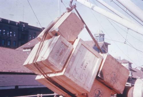 Slide depicting a stack of wooden crates being lifted by a crane