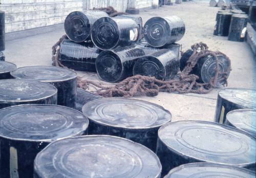 Slide depicting collection of balck barrels on the wharf