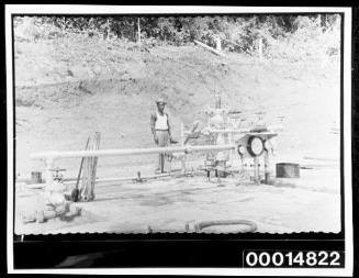 A man stands besides pipes at a work site, Trinidad, West Indies