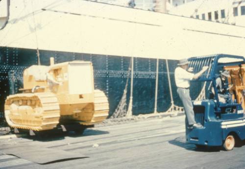 Slide depicting a man riding on the back of a fork lift