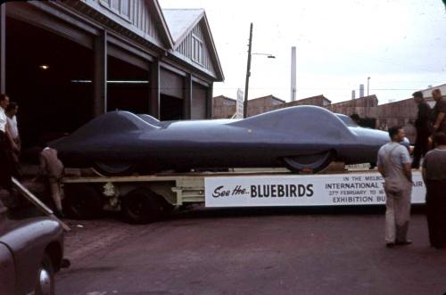 Slide depicting a row of three sheds the bluebird car on a trailor