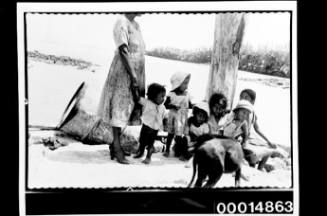 A woman stands beside several children on a Galapagos Island beach